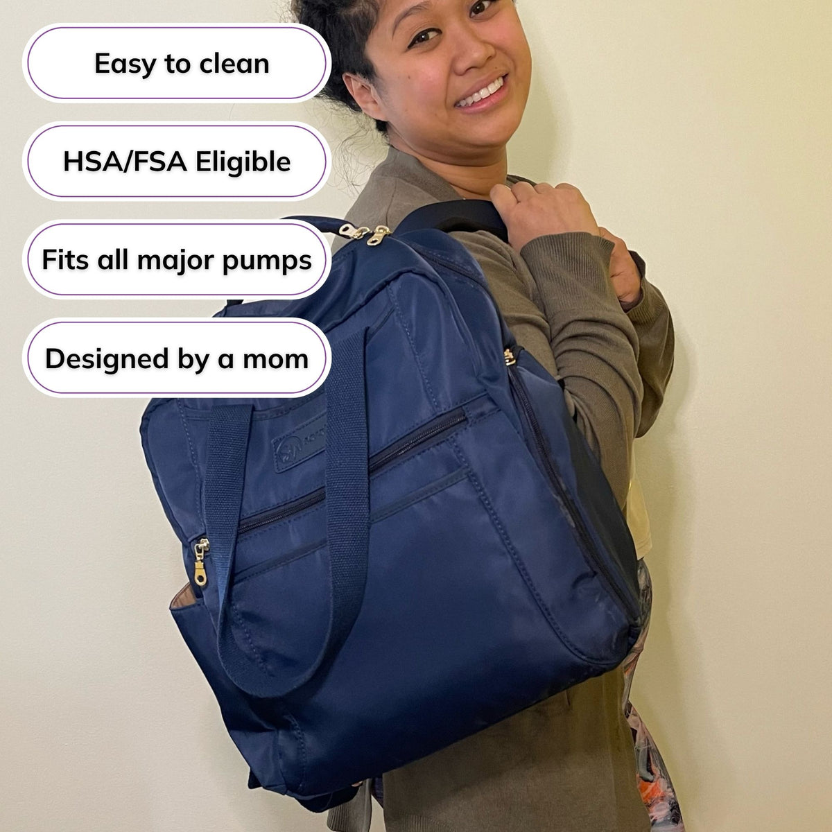 Woman carrying the Sarah Wells Kelly pump bag in Indigo, with badges for easy to clean, HSA/FSA eligible, fits all major pumps, and designed by a mom