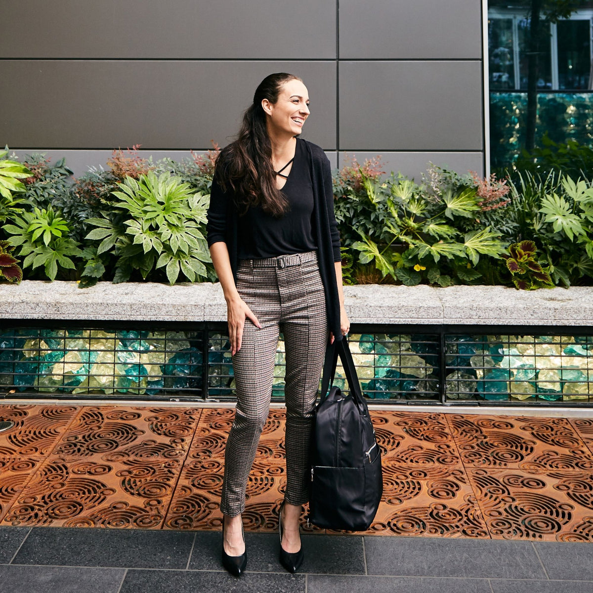 Woman wearing the Sarah Wells Kelly pump bag in Black carrying it as a tote
