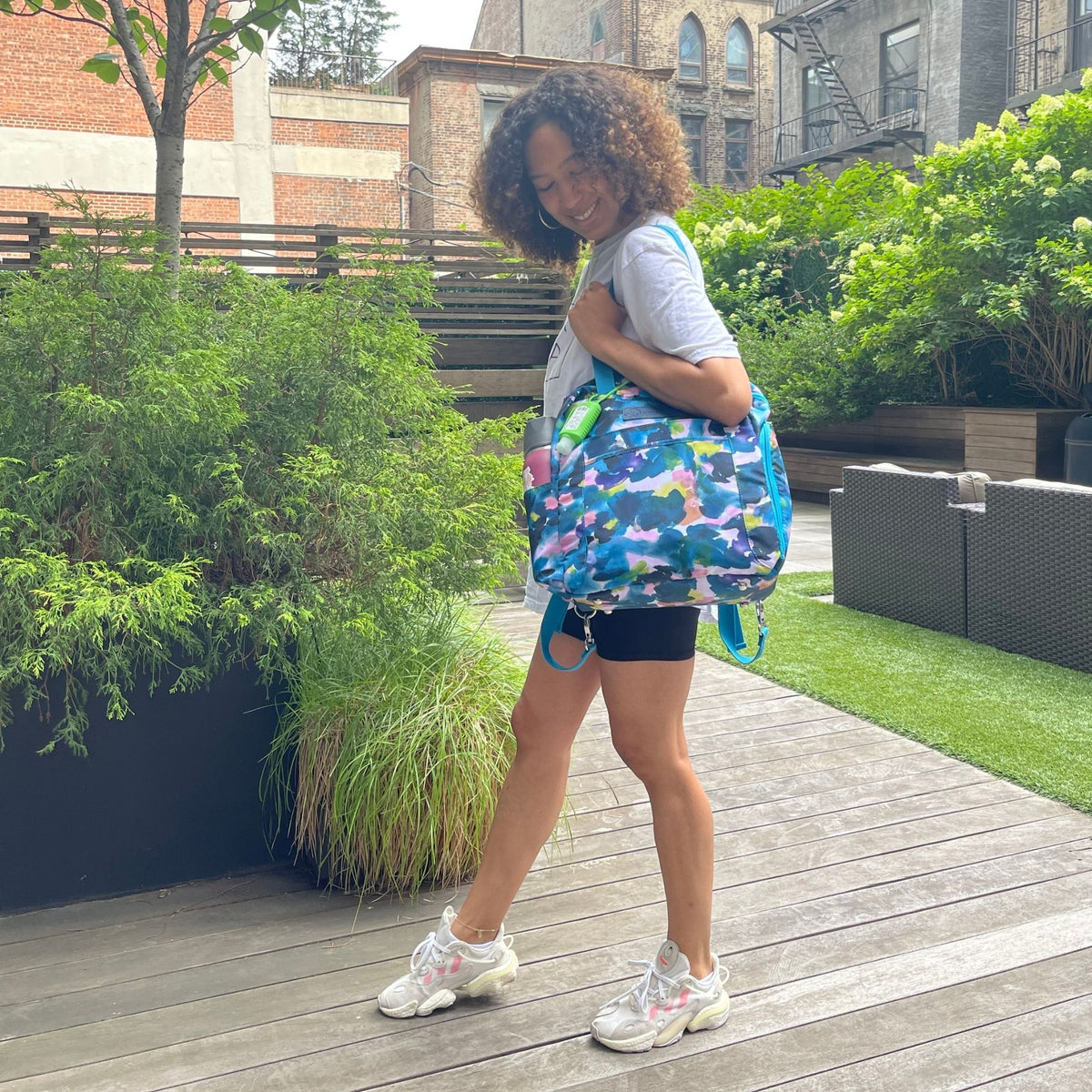 Woman wearing the Sarah Wells Kelly pump bag in aquarelle carrying it as a tote