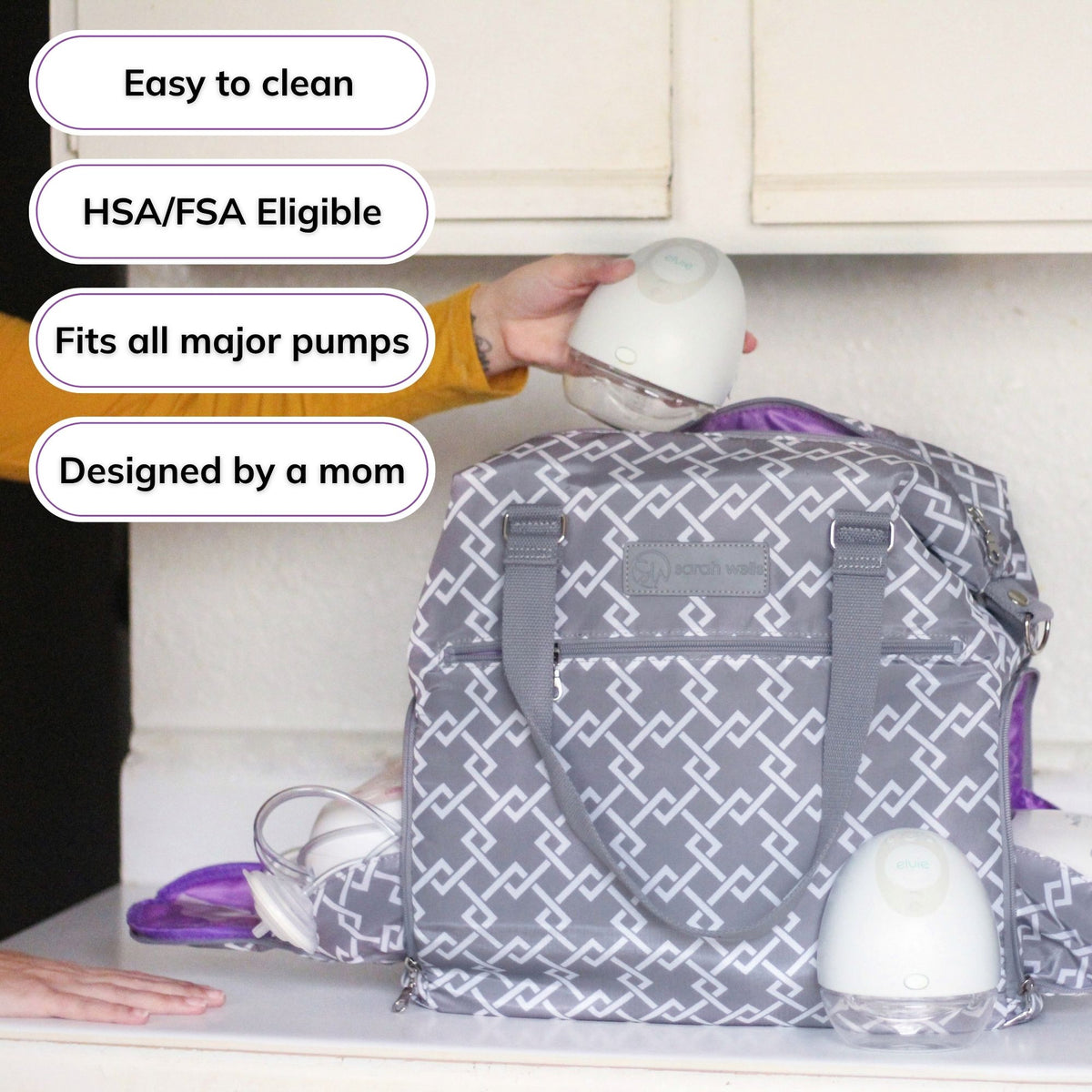 Woman carrying the Sarah Wells Lizzy pump tote in gray, with badges for easy to clean, HSA/FSA eligible, fits all major pumps, and designed by a mom