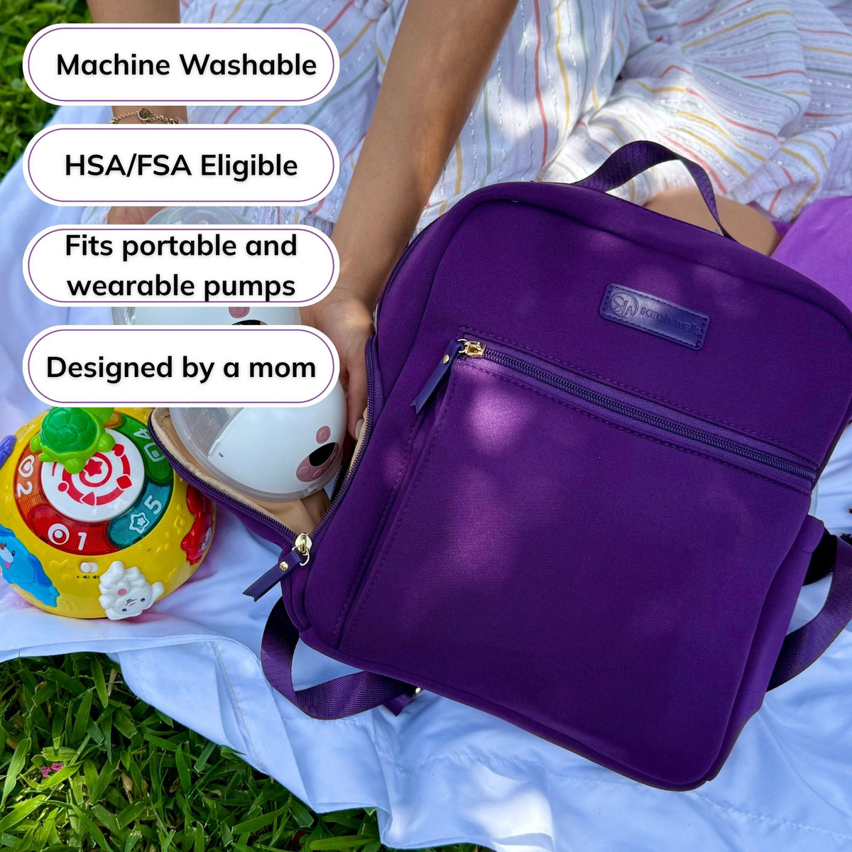 Woman carrying the Sarah Wells Fifi mini pump backpack in Purple, with badges for machine washable, HSA/FSA eligible, fits portable and wearable pumps, and designed by a mom
